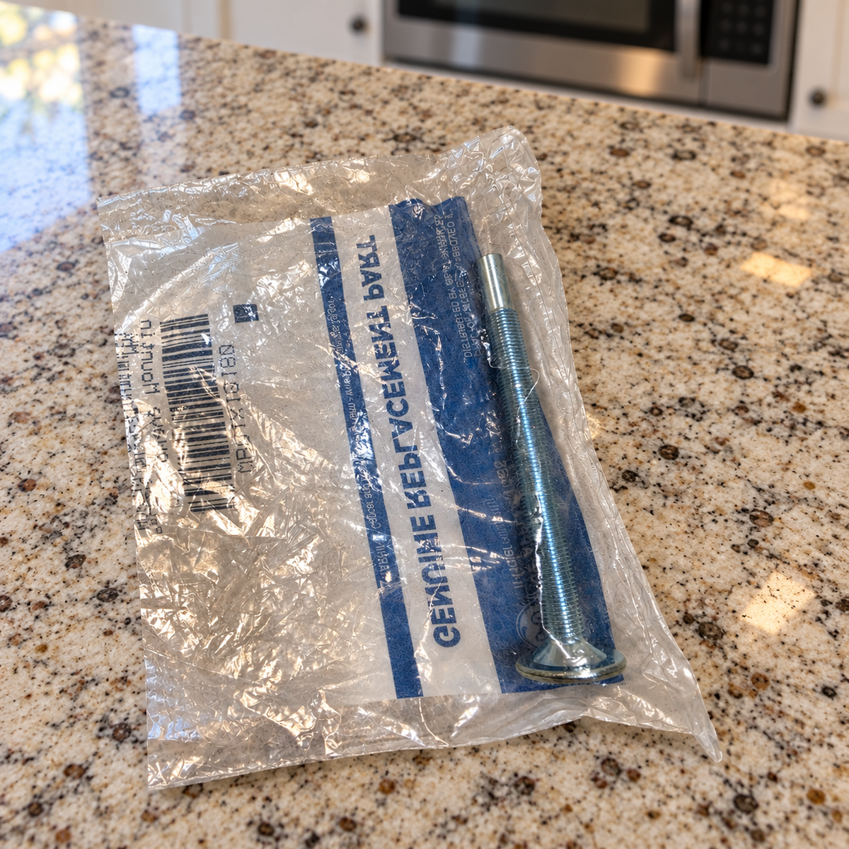 Packaged GE mounting bolt on a kitchen counter with a closed microwave in the background.
