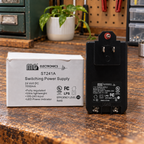 AI-generated lifestyle illustration of the unplugged MG ST241A power supply and original box in an indoor workshop setting.