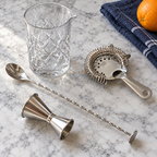 AI-generated lifestyle illustration of the four-piece Silver One cocktail mixing set arranged on a pale stone counter.