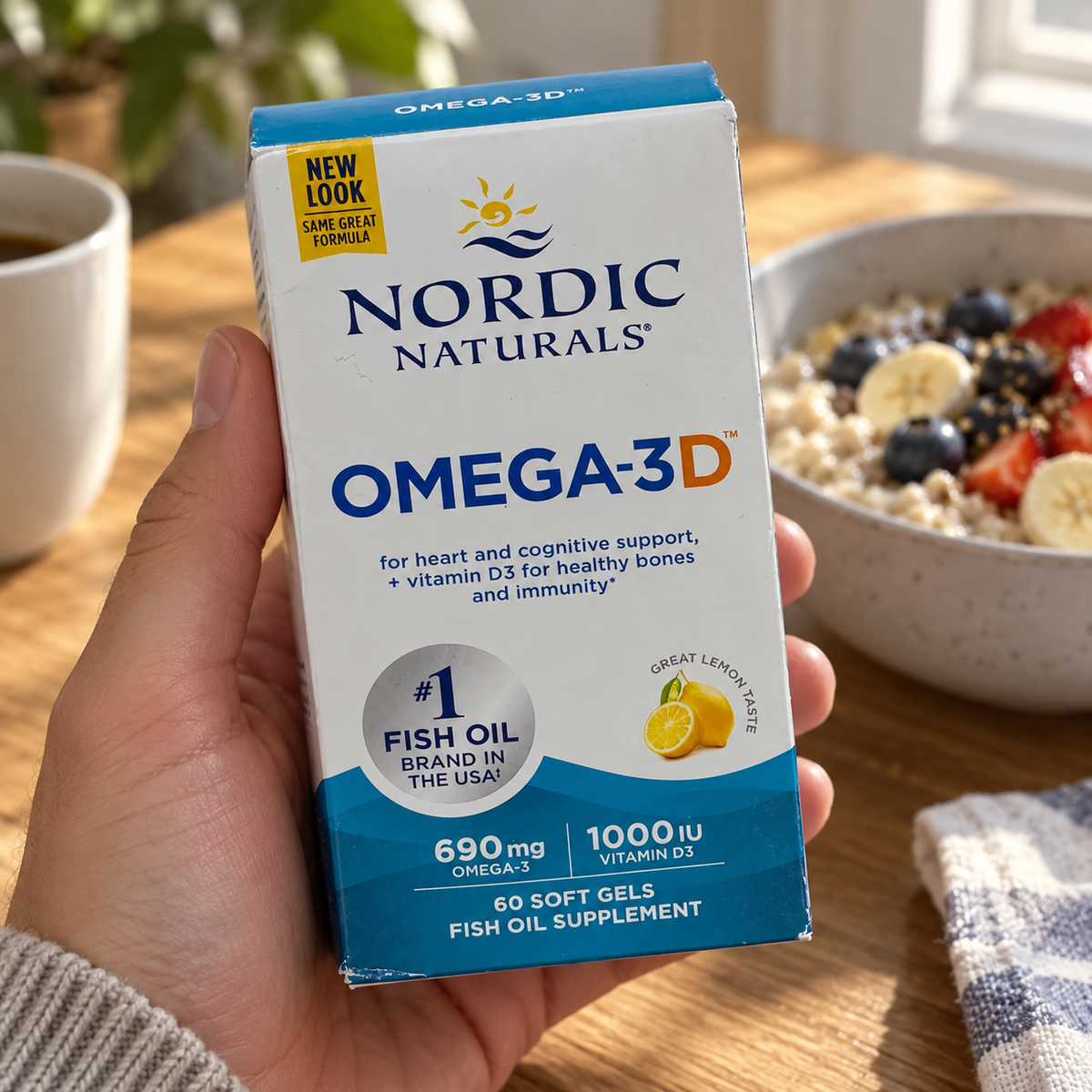 An adult holding a Nordic Naturals Omega-3D 60-soft-gel box at a breakfast table