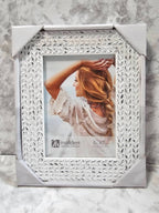 Decorative white photo frame with intricate patterns on a marble surface