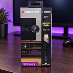 Monster purple LED HDMI cable retail package on a walnut gaming desk