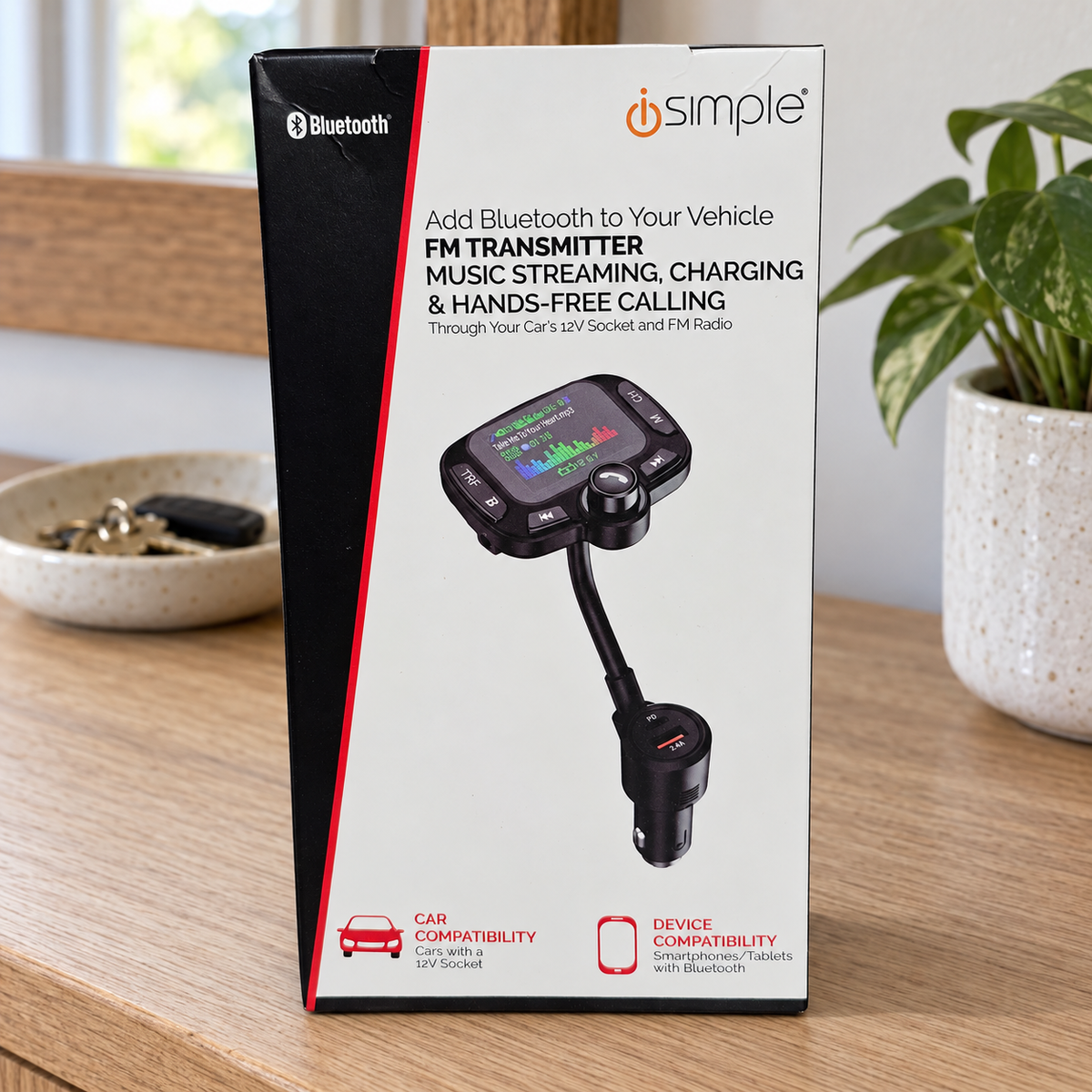 iSimple FMBTIS Bluetooth FM transmitter retail box on an oak entryway console beside a key dish
