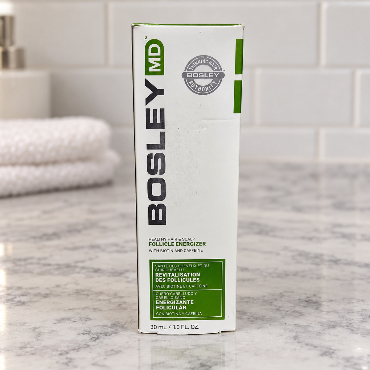 BosleyMD Follicle Energizer carton on a pale stone vanity beside folded towels