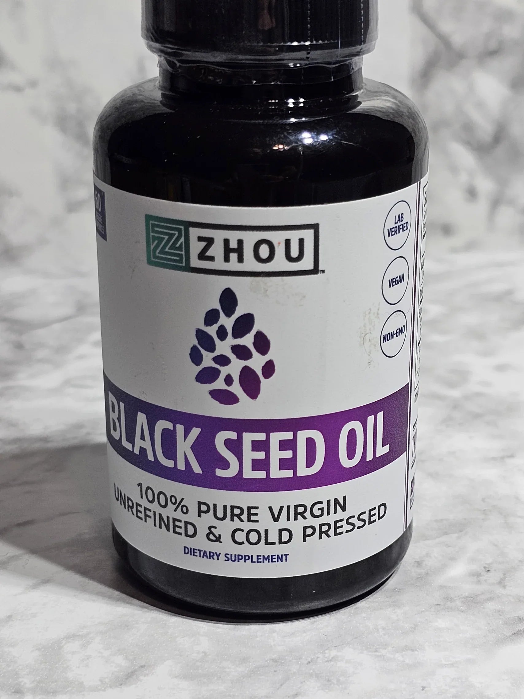 Bottle of Zhou Black Seed Oil on a textured gray background
