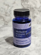 Blue supplement bottle labeled 'Motherlove Morning Sings Blend' on a gray marble surface