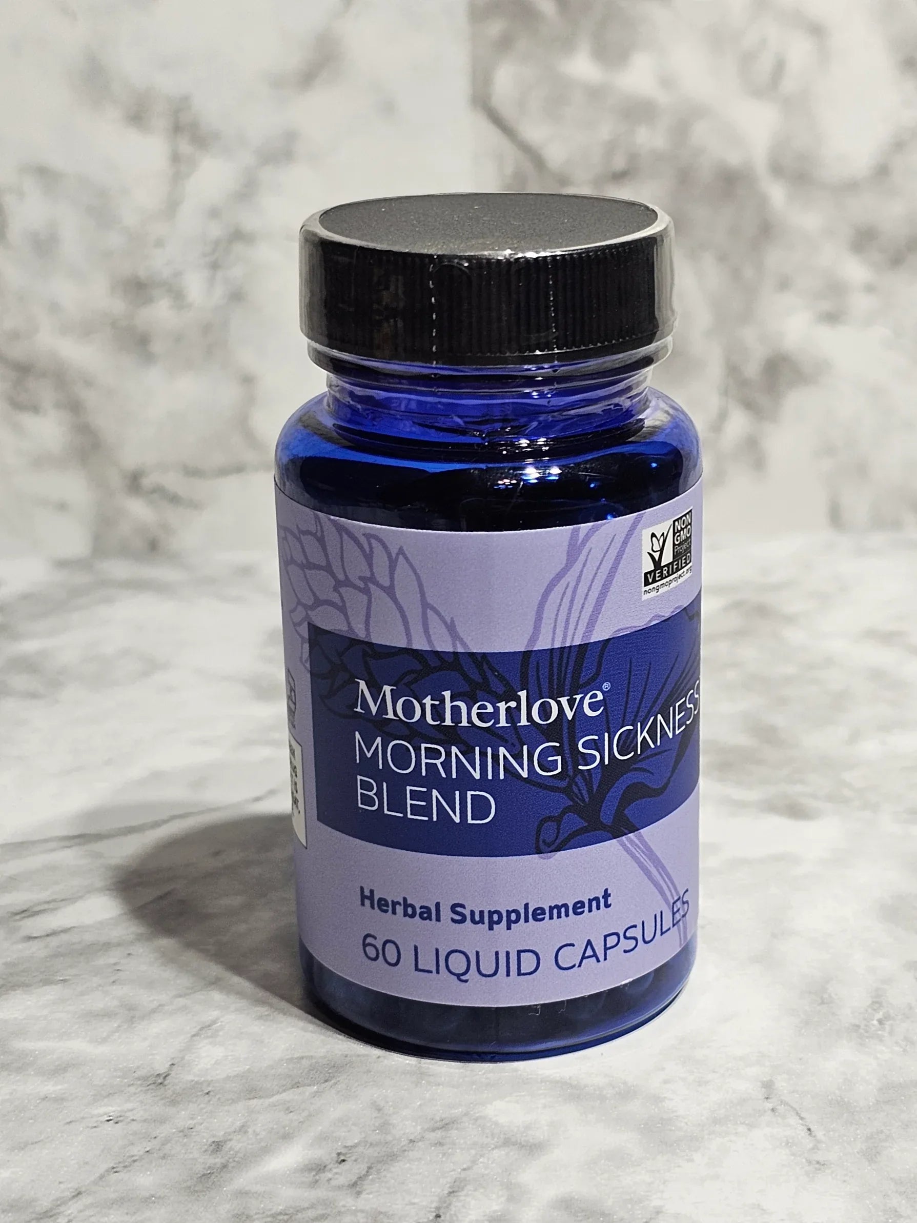 Blue supplement bottle labeled 'Motherlove Morning Sings Blend' on a gray marble surface