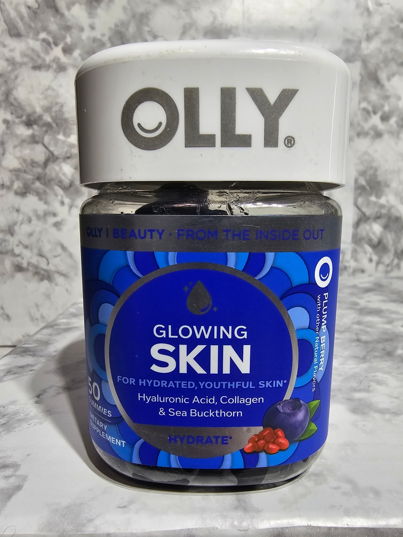 OLLY Glowing Skin supplement bottle on a marble surface