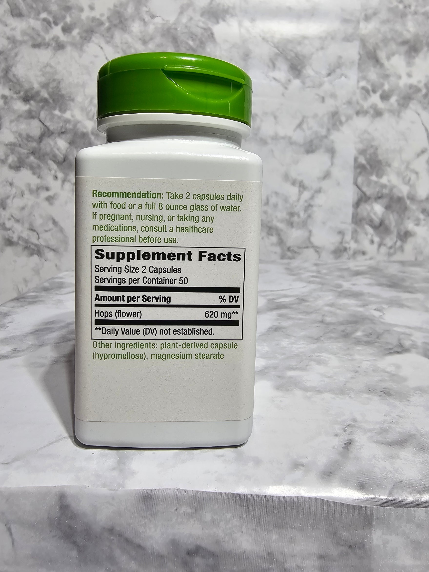 Supplement bottle with green cap on a marble surface