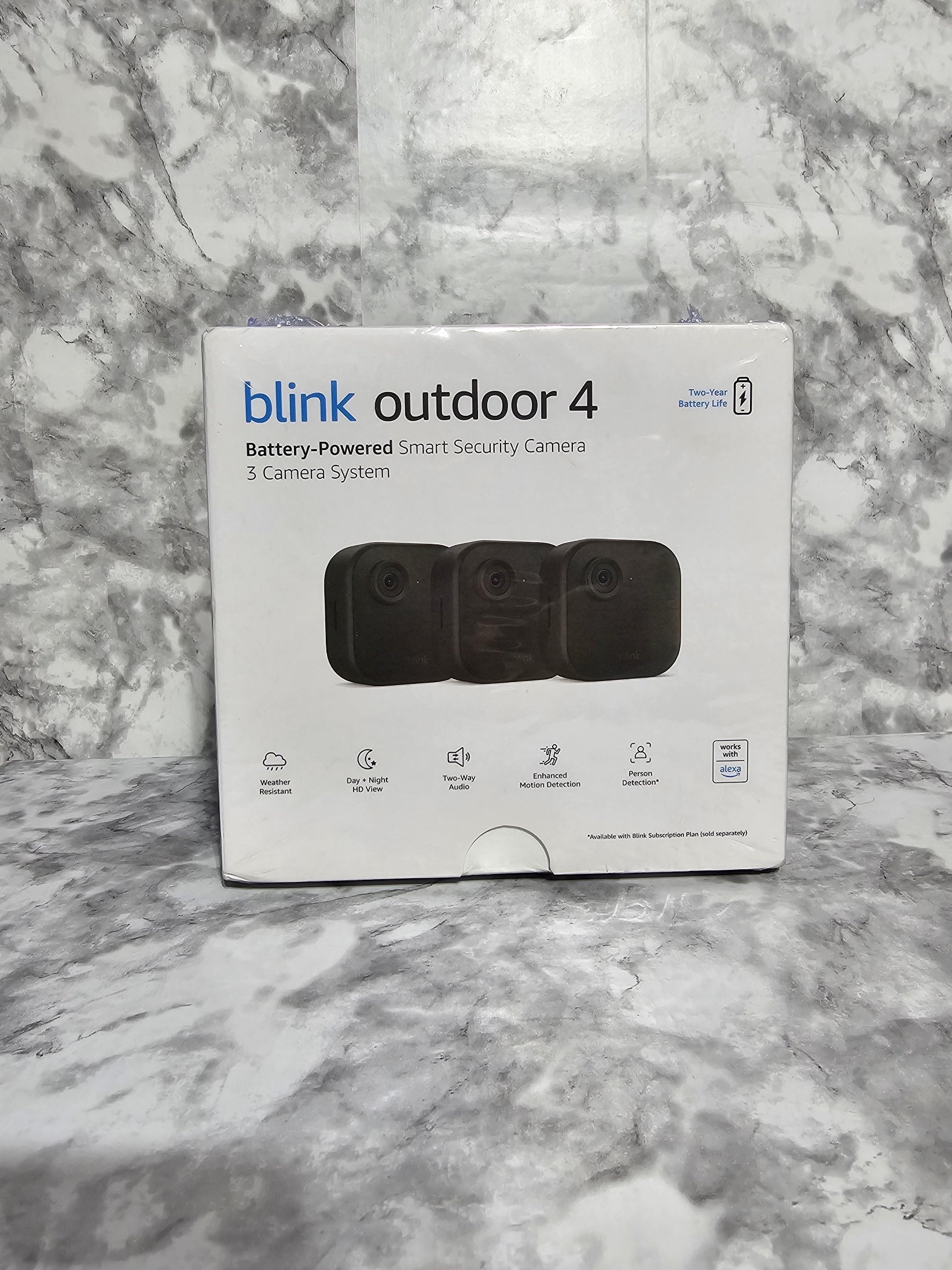 Blink Outdoor 4 security camera packaging on a marble surface