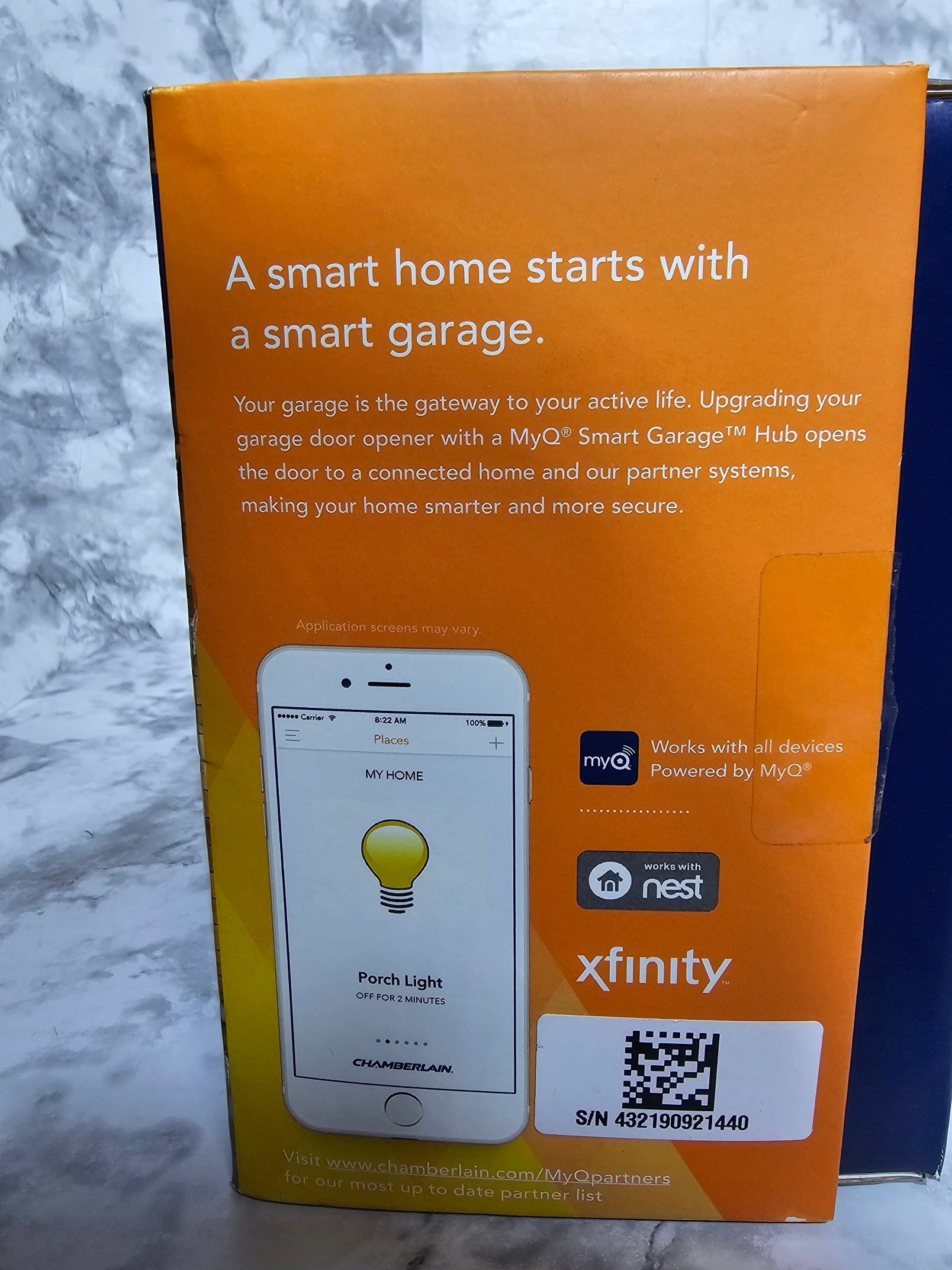 Orange box with smartphone app interface and Xfinity branding on a marble surface