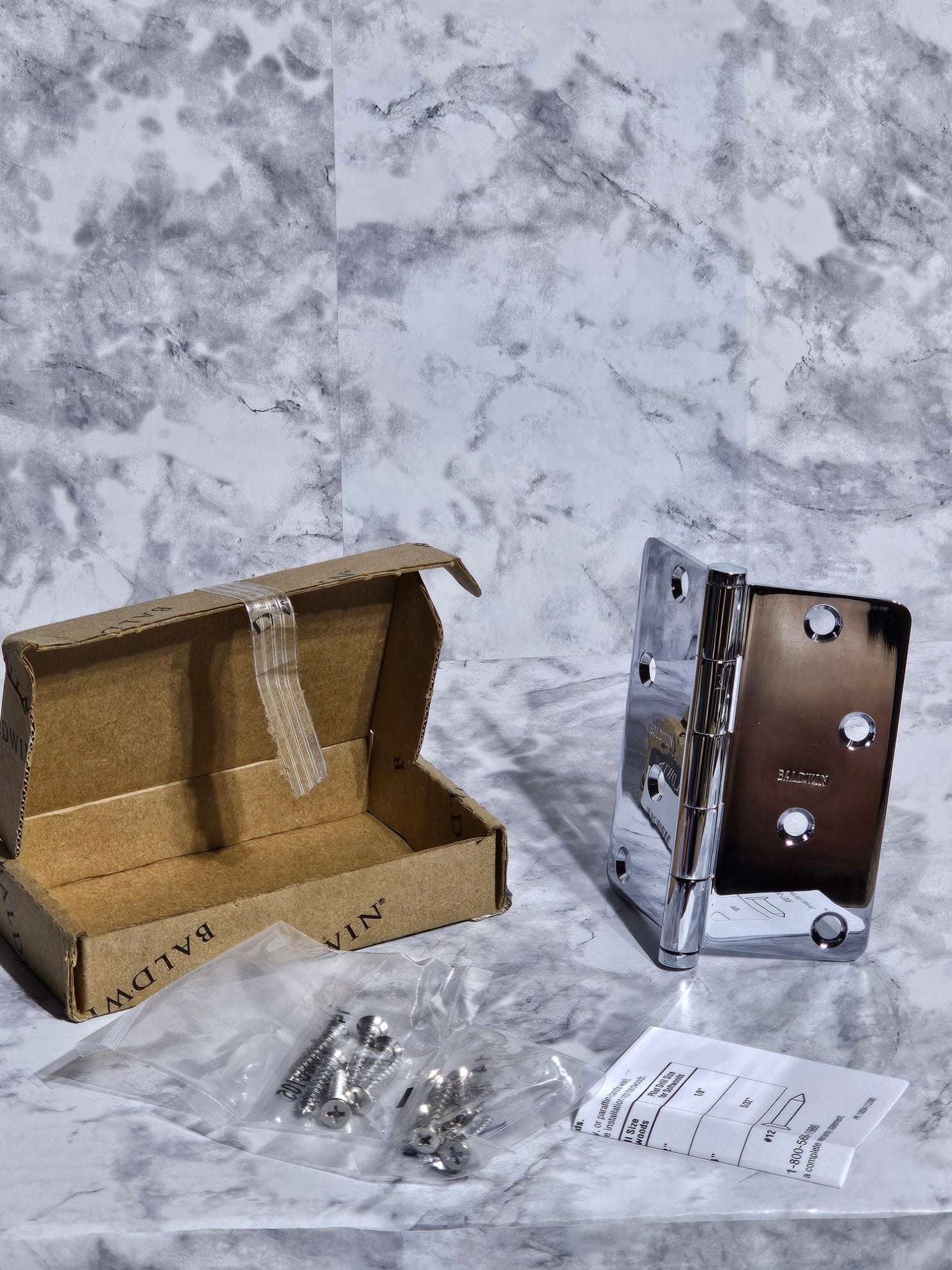 Metal bracket on a marble surface with a cardboard box and screws nearby