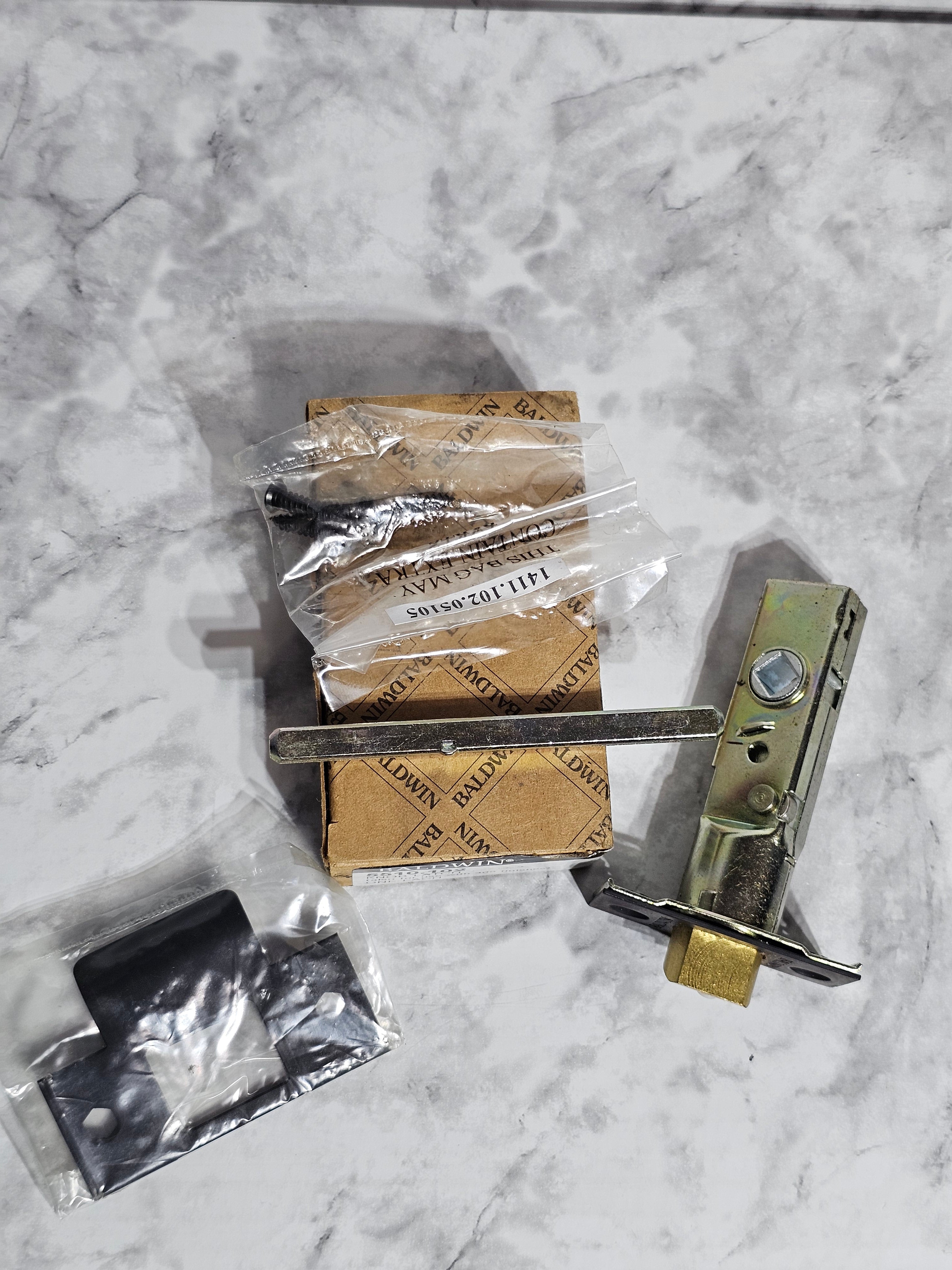 Metal lock mechanism on a marble surface with packaging materials.