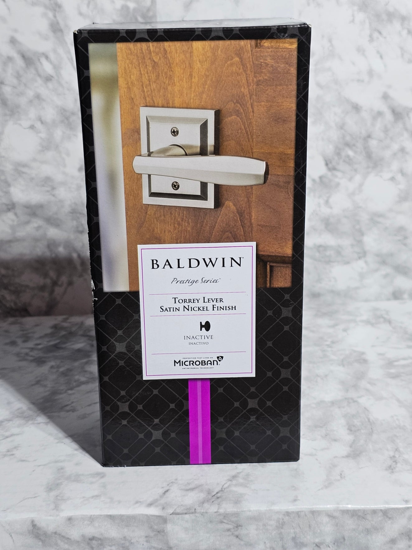 Wooden door handle set in a black box with Baldwin label on marble surface