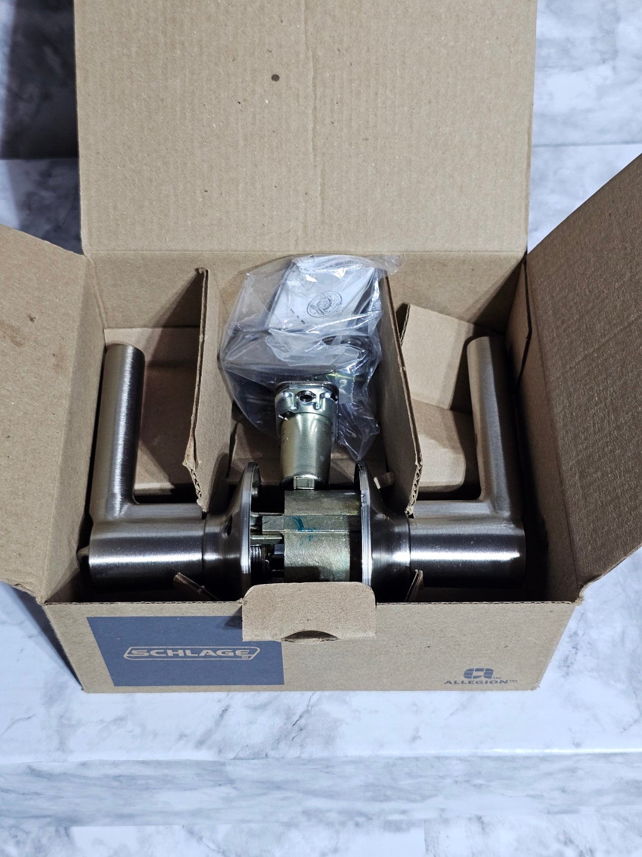 Metal door handle in a cardboard box on a marble surface