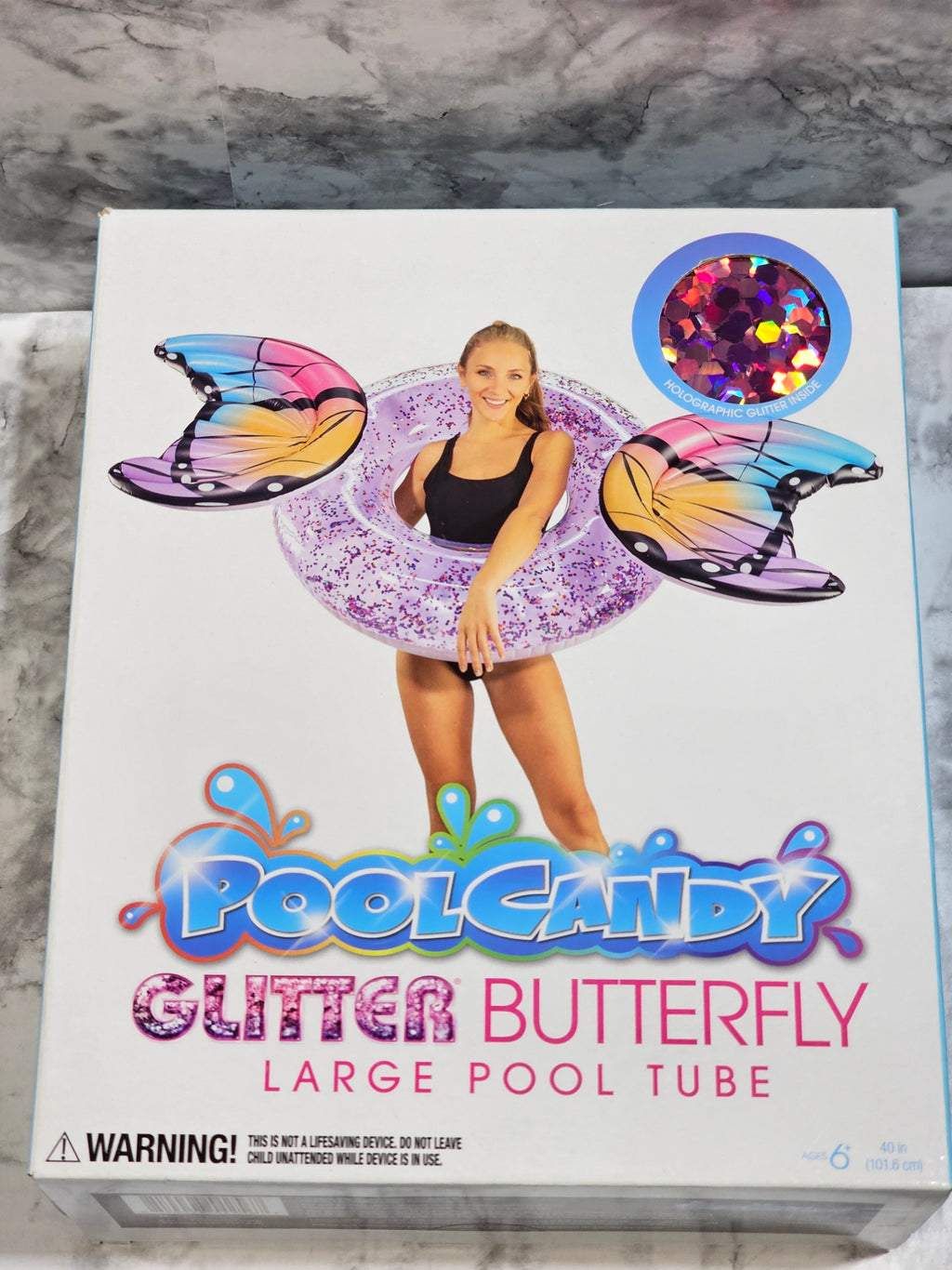 Box of PoolCandy Glitter Butterfly large pool tube on a marble surface