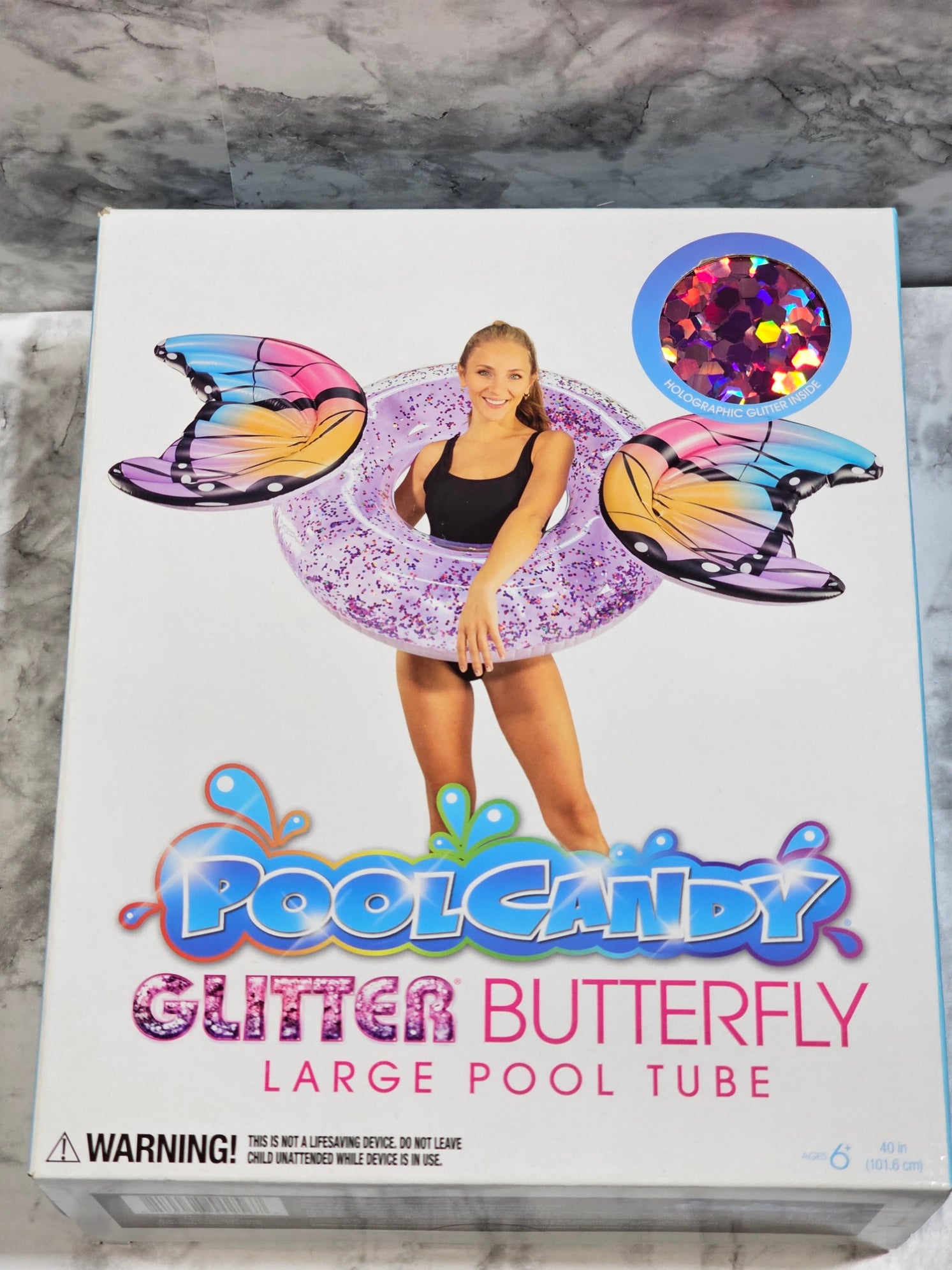 Box of PoolCandy Glitter Butterfly large pool tube on a marble surface