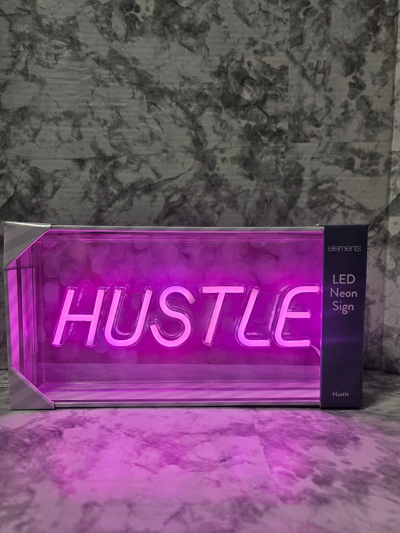 Neon sign with the word 'HUSTLE' on a marble surface