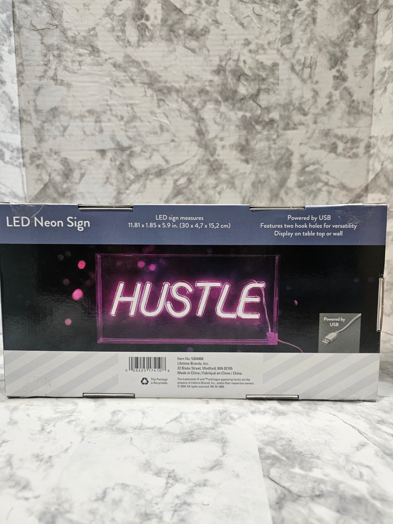 Neon sign packaging with 'HUSTLE' text on a marble surface