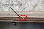 Close-up of a door with a small hole and a gold object inside, next to a marble surface.