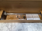 Open cardboard box containing a clear rod and plastic components on a marble surface
