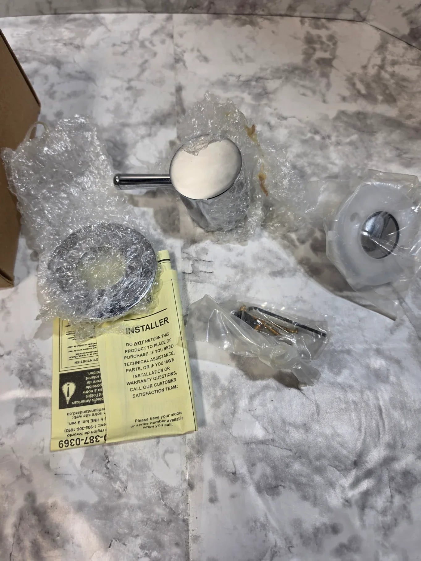 Bathroom fixtures and tools on a marble countertop with a Stihl tool box.