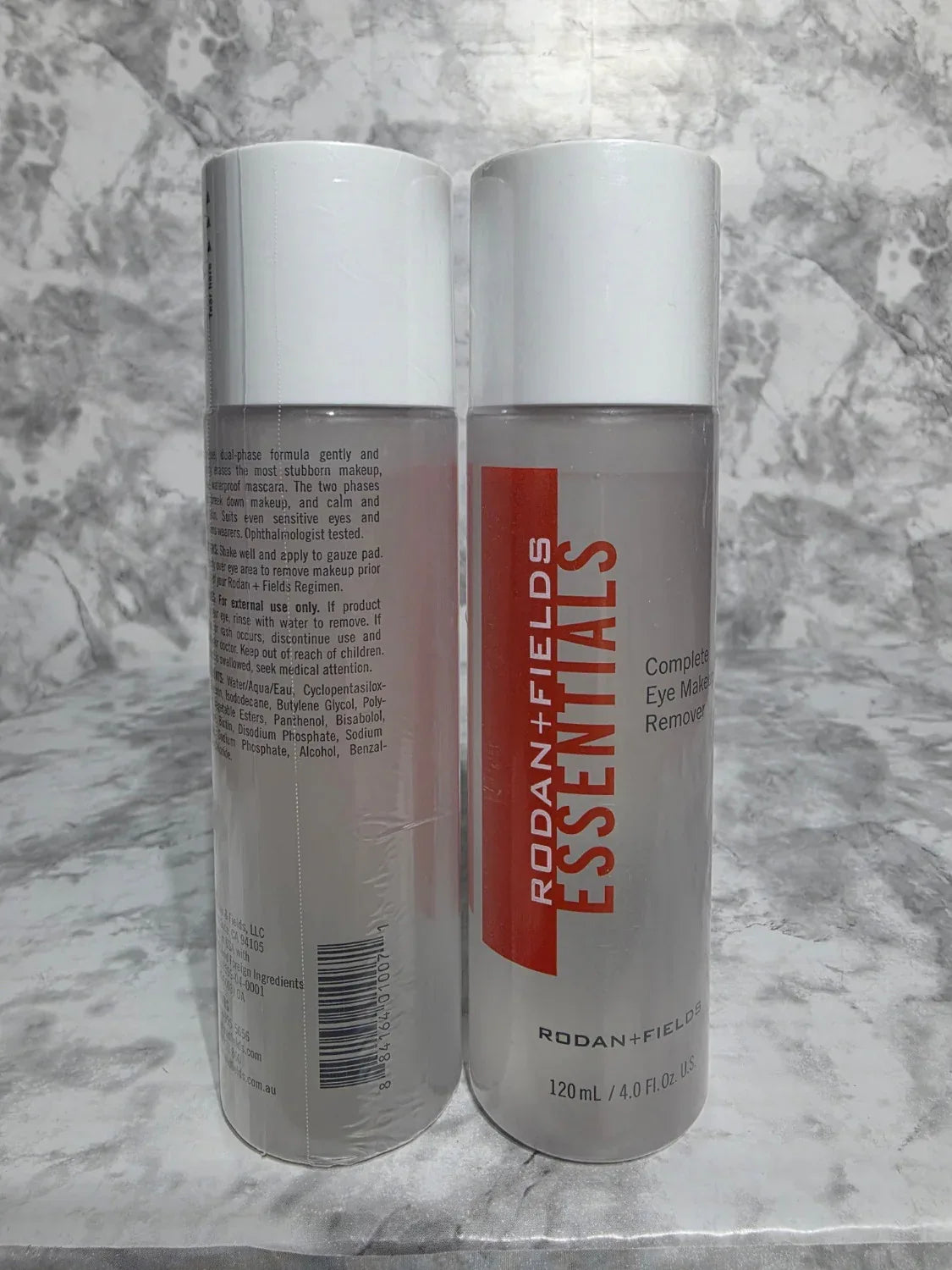 Two Rodan + Fields Essentials skincare bottles on a marble surface