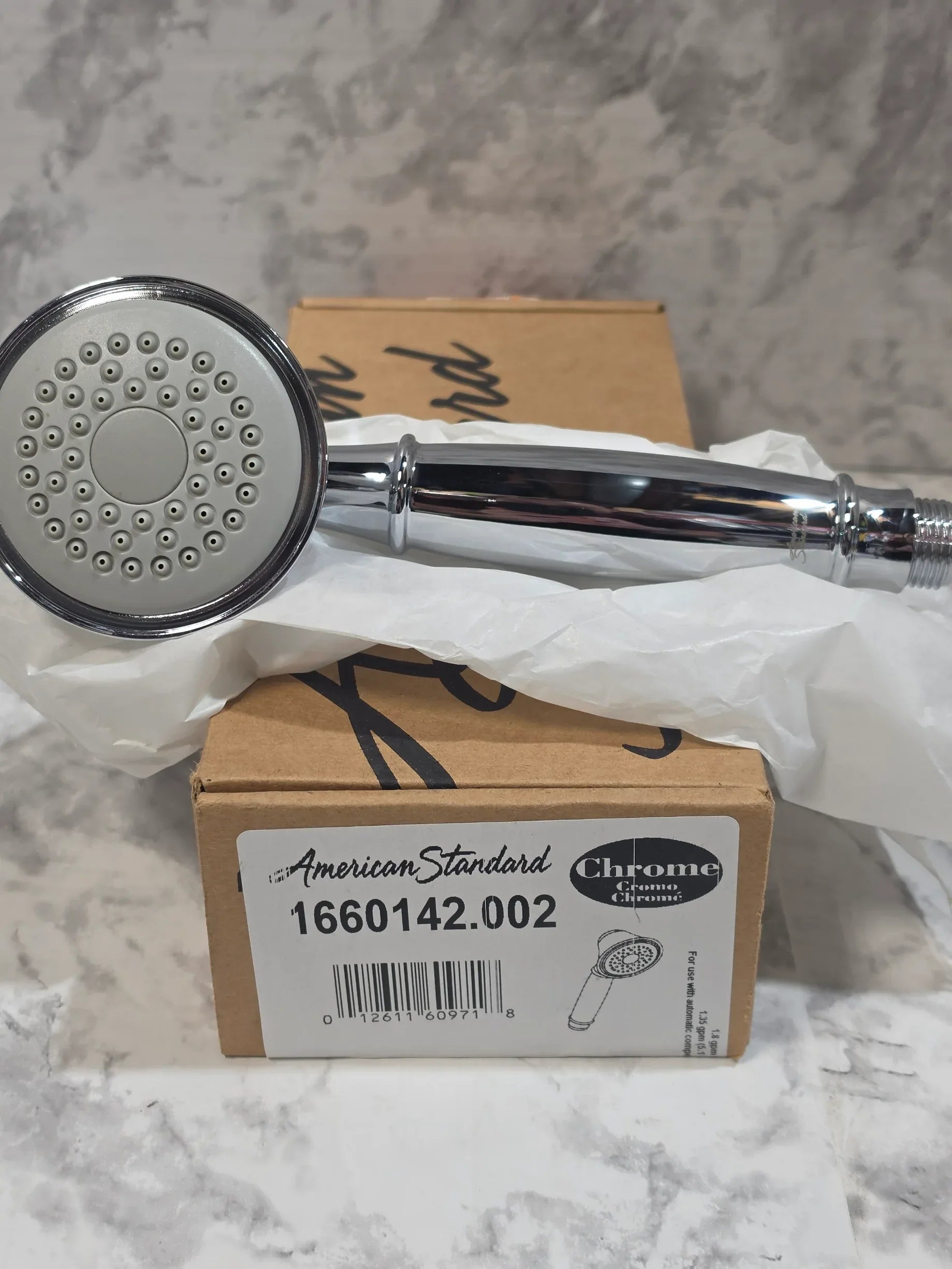 Chrome shower head with packaging on a marble surface