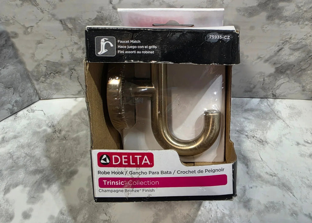 Gold robe hook in packaging on a marble surface
