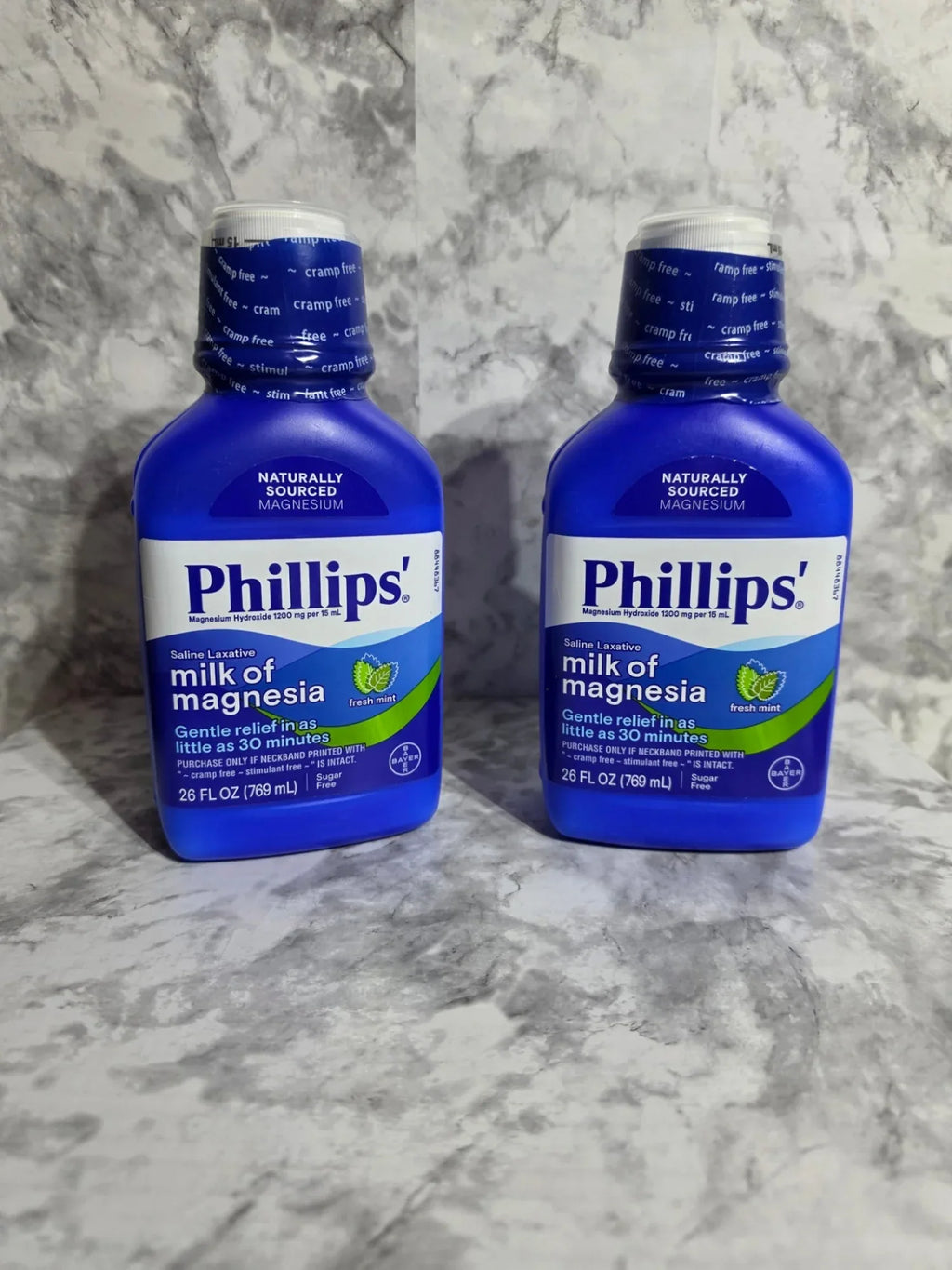 Two bottles of Phillips' Milk of Magnesia on a gray marble surface