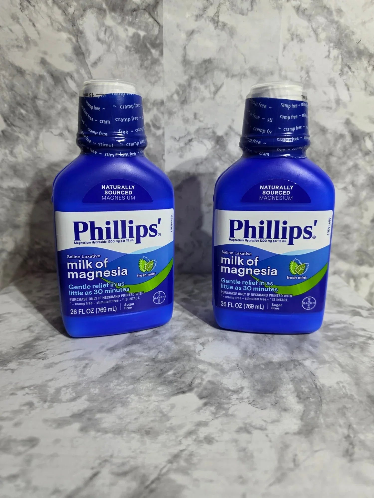 Two bottles of Phillips' Milk of Magnesia on a gray marble surface