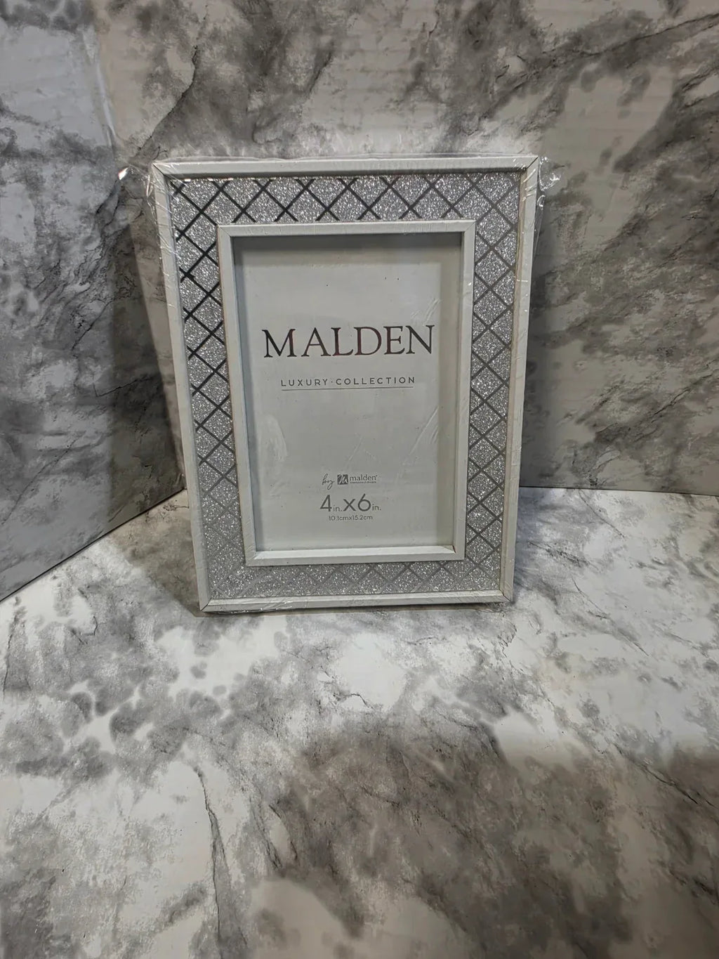 Silver picture frame with 'Malden' branding on a marble surface