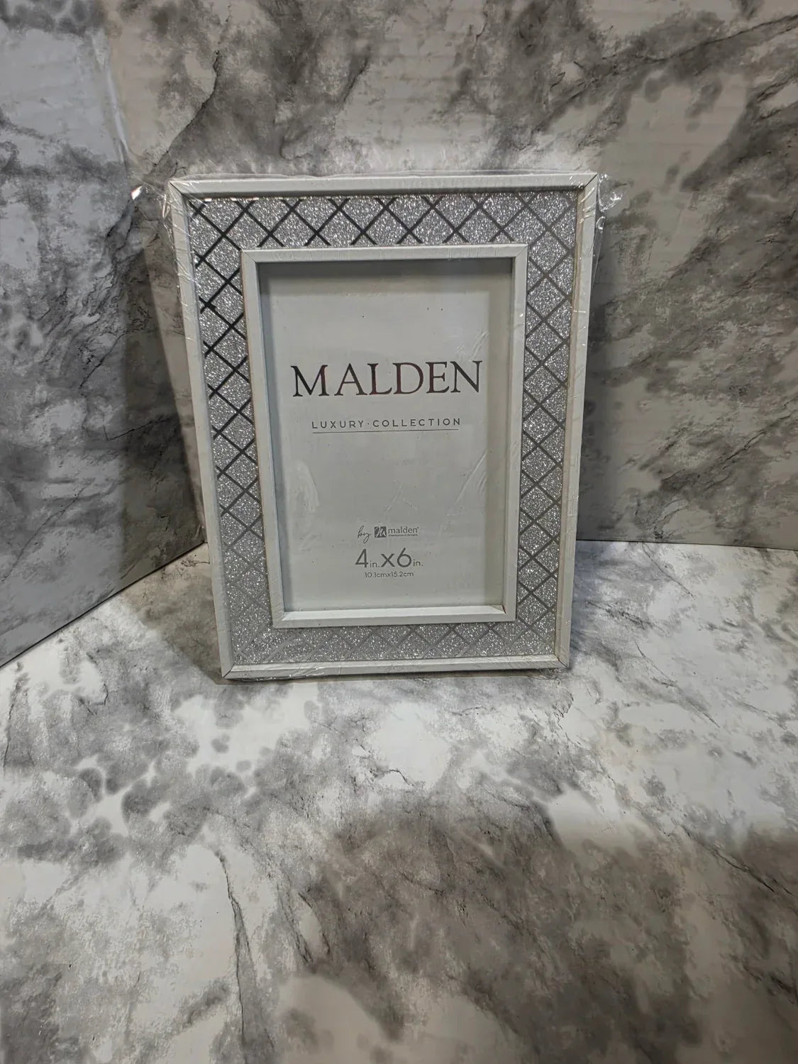 Silver picture frame with 'Malden' branding on a marble surface