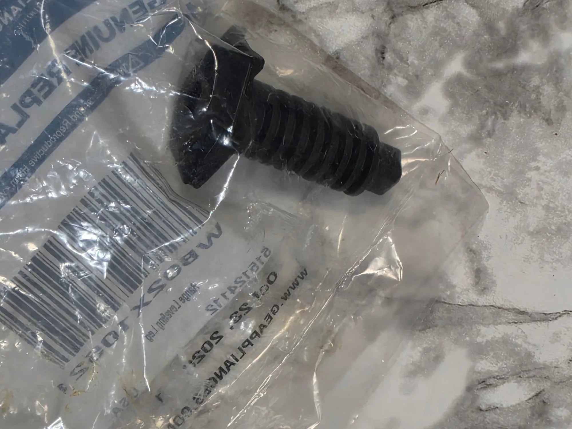 Black rubber grommet in clear plastic packaging on a marble surface