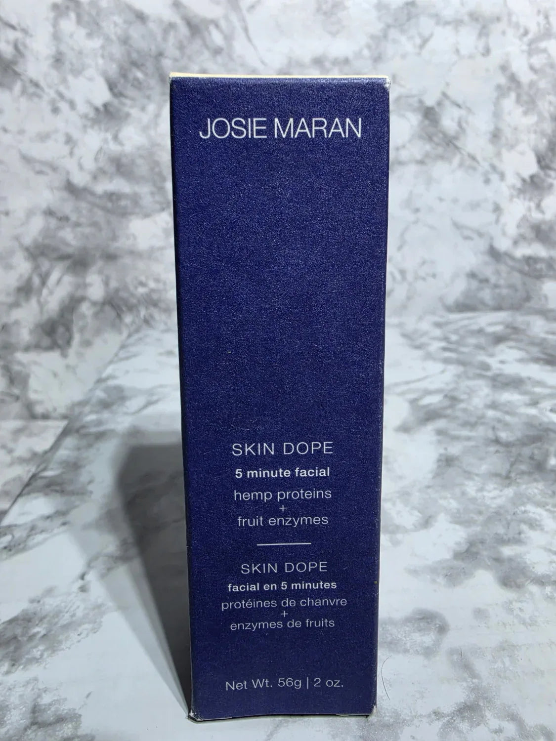 Josie Maran Skin Dope product packaging on a marble surface