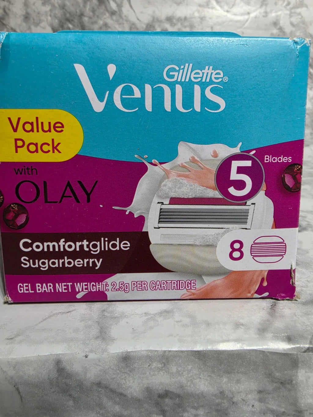 Gillette Venus razor packaging with Olay Comfortglide Sugarberry gel bar on a marble surface
