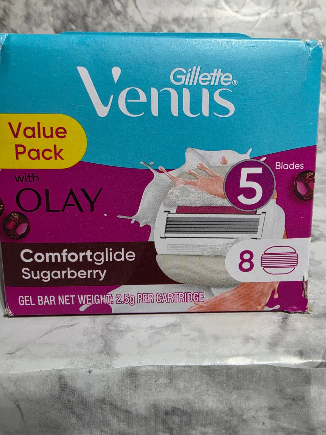 Gillette Venus razor packaging with Olay Comfortglide Sugarberry gel bar on a marble surface