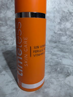 Orange skincare product tube with text on a gray marble background