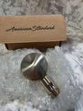 Metallic shower handle with packaging labeled 'American Standard' on a marble surface.