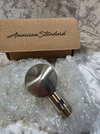 Metallic shower handle with packaging labeled 'American Standard' on a marble surface.
