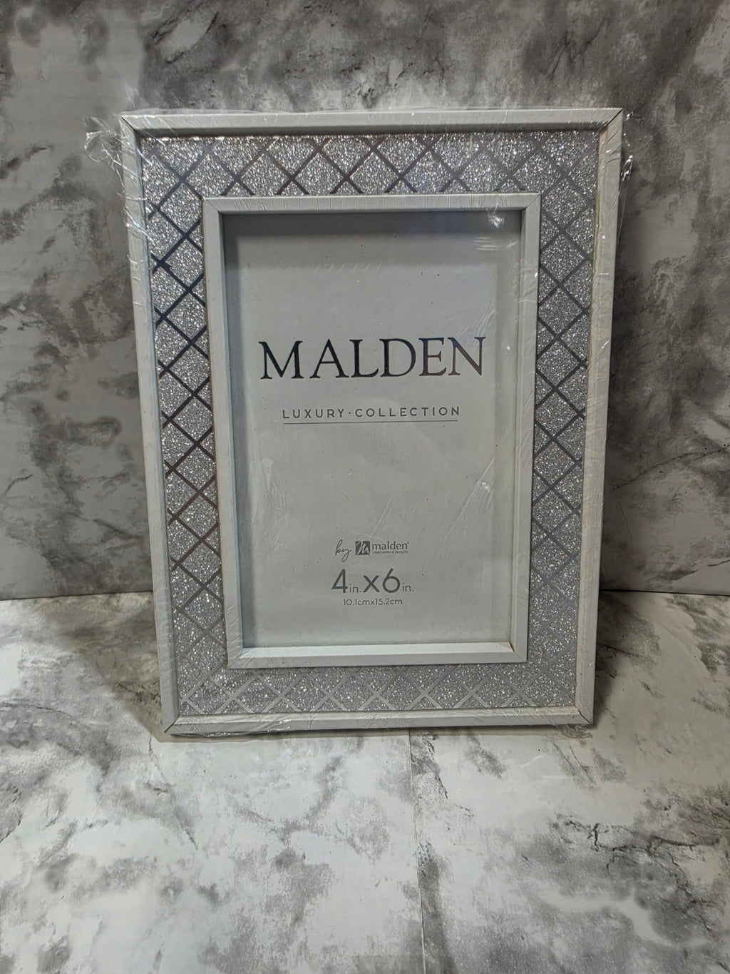Decorative picture frame with 'Malden' branding on a marble surface