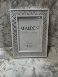 Decorative picture frame with 'Malden' branding on a marble surface