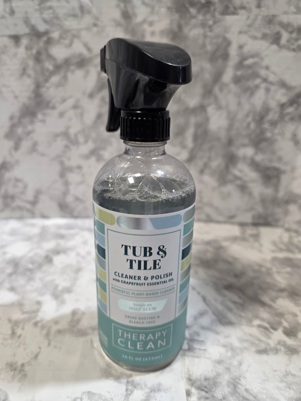 Bottle of 'Tubs & Tile' cleaner on a textured gray surface