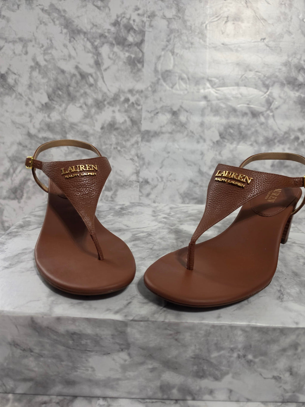Pair of brown sandals on a gray marble surface