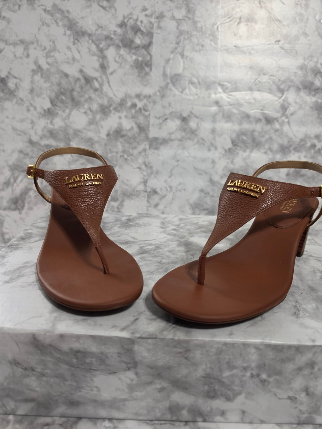 Pair of brown sandals on a gray marble surface