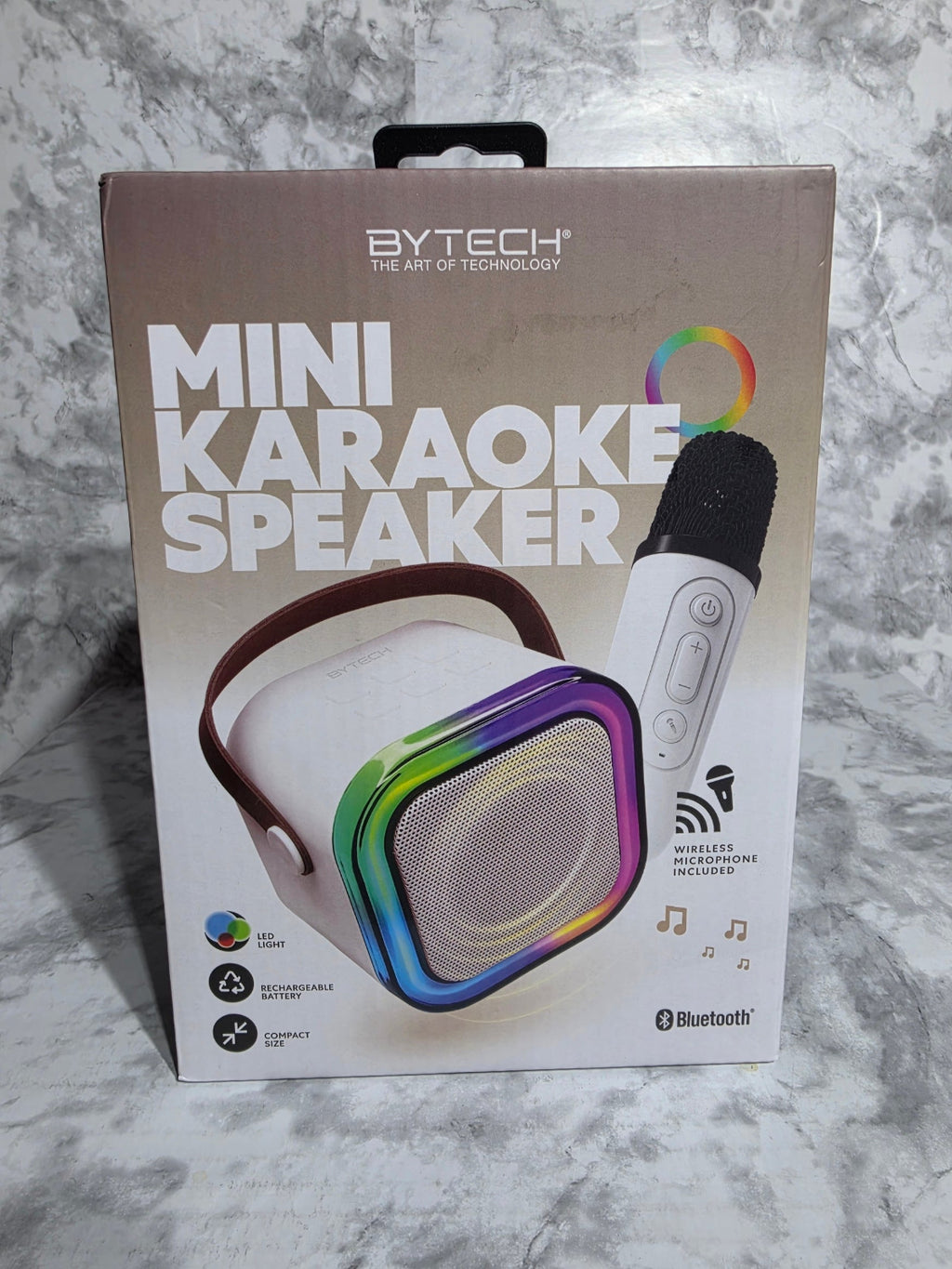 Box of a mini karaoke speaker with colorful design on a marble surface