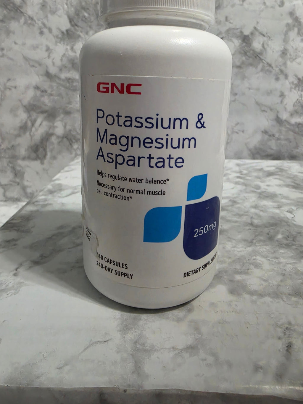GNC potassium and magnesium aspartate supplement bottle on a marble surface