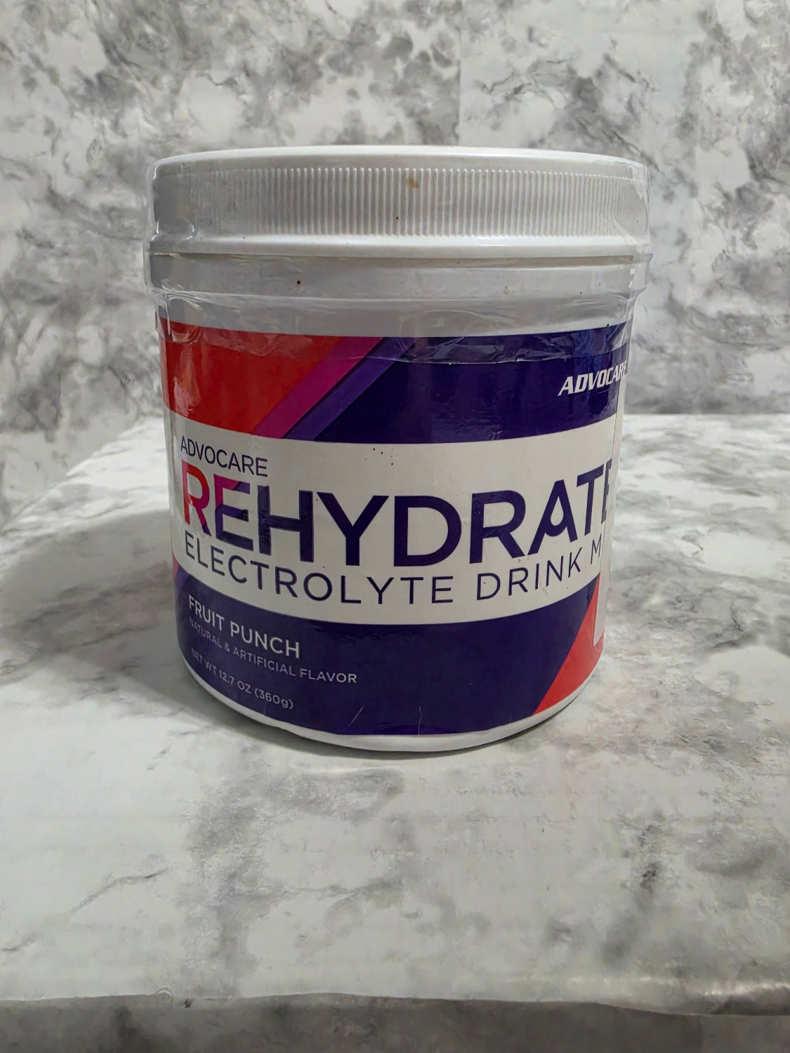 Container of Rehydrate electrolyte drink mix on a marble surface