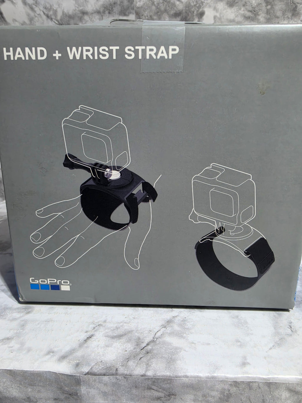Box for a hand and wrist strap with illustrations on a marble surface