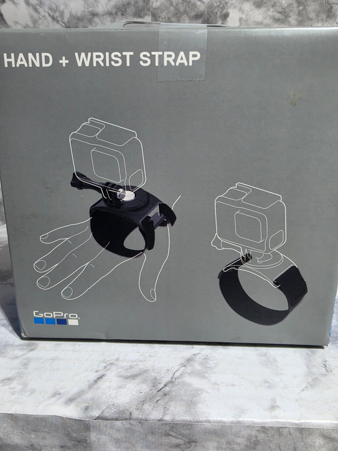 Box for a hand and wrist strap with illustrations on a marble surface
